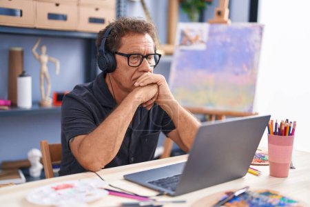 Foto de Hombre de mediana edad artista usando portátil en el estudio de arte - Imagen libre de derechos