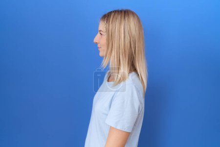 Photo for Young caucasian woman wearing casual blue t shirt looking to side, relax profile pose with natural face and confident smile. - Royalty Free Image