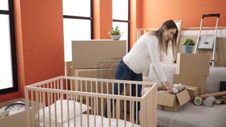Photo for Young pregnant woman preparing baby cradle at new home - Royalty Free Image
