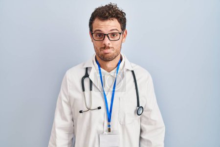 Photo for Young hispanic man wearing doctor uniform and stethoscope depressed and worry for distress, crying angry and afraid. sad expression. - Royalty Free Image