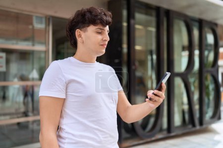 Photo for Non binary man using smartphone with relaxed expression at street - Royalty Free Image