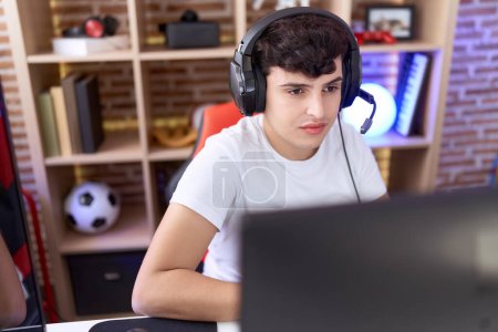 Téléchargez les photos : Non binary man streamer playing video game using computer at gaming room - en image libre de droit