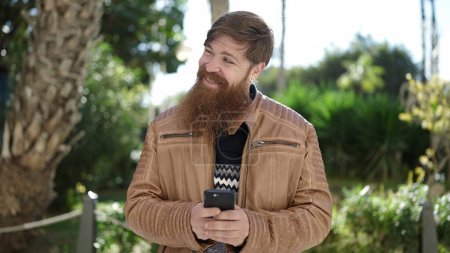 Téléchargez les photos : Young redhead man smiling confident using smartphone at park - en image libre de droit
