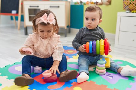 Photo for Adorable boy and girl playing with hoops game sitting on floor at kindergarten - Royalty Free Image