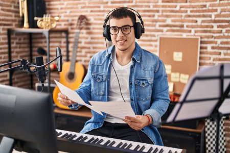 Téléchargez les photos : Jeune musicien tenant une partition musicale au studio de musique - en image libre de droit