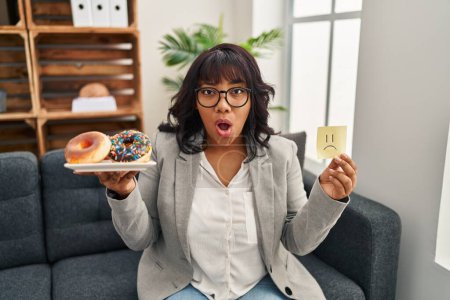 Photo for Hispanic therapist woman working on eating disorder afraid and shocked with surprise and amazed expression, fear and excited face. - Royalty Free Image
