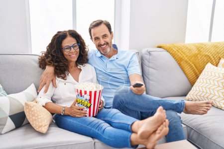 Téléchargez les photos : Man and woman couple watching movie sitting on sofa at home - en image libre de droit