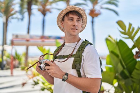 Photo for Young caucasian man tourist holding vintage camera at park - Royalty Free Image