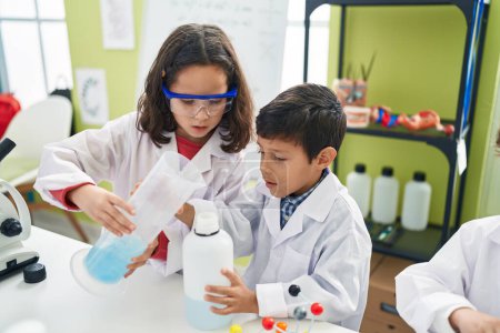 Foto de Adorable niño y niña estudiante vertiendo líquido en el tubo de ensayo en el aula de laboratorio - Imagen libre de derechos