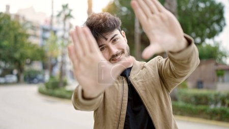 Photo for Young hispanic man smiling confident doing frame gesture with hands at park - Royalty Free Image
