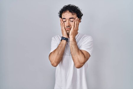 Téléchargez les photos : Homme hispanique debout sur fond isolé mains fatiguées couvrant le visage, la dépression et la tristesse, bouleversé et irrité par le problème - en image libre de droit