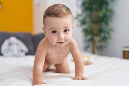 Photo for Adorable caucasian baby crawling on bed at bedroom - Royalty Free Image
