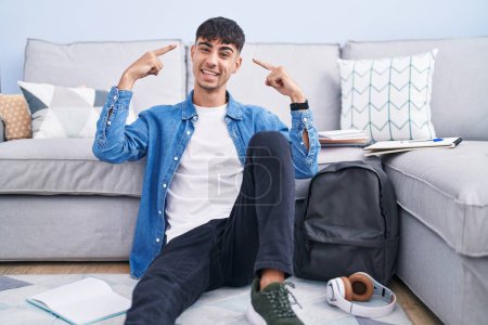 Photo for Young hispanic man sitting on the floor studying for university smiling pointing to head with both hands finger, great idea or thought, good memory - Royalty Free Image