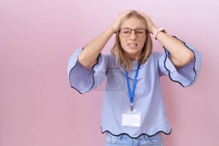 Photo for Young caucasian business woman wearing id card suffering from headache desperate and stressed because pain and migraine. hands on head. - Royalty Free Image