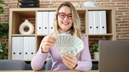 Photo for Young blonde woman business worker using laptop counting dollars at office - Royalty Free Image