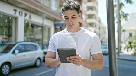 Téléchargez les photos : Young hispanic man using touchpad at street - en image libre de droit