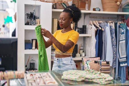 Photo for African american woman shop assistant folding clothes working at clothing store - Royalty Free Image