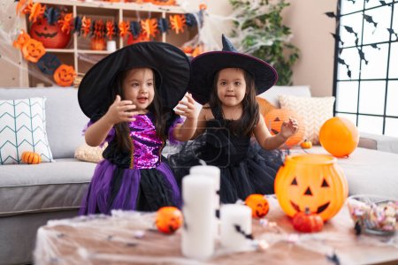Téléchargez les photos : Adorable jumelles ayant fête d'Halloween souriant confiant à la maison - en image libre de droit