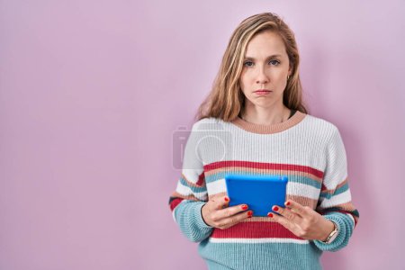 Photo for Young blonde woman holding touchpad skeptic and nervous, frowning upset because of problem. negative person. - Royalty Free Image