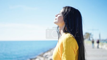 Téléchargez les photos : Jeune belle femme hispanique respirant les yeux fermés au bord de la mer - en image libre de droit