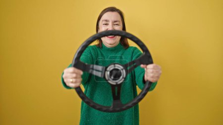 Photo for Mature hispanic woman with grey hair smiling confident using steering wheel over isolated yellow background - Royalty Free Image