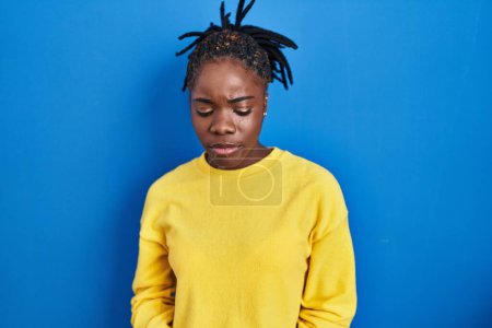 Téléchargez les photos : Belle femme noire debout sur fond bleu déprimé et inquiet pour la détresse, pleurer en colère et effrayé. triste expression. - en image libre de droit