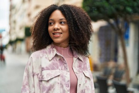 Téléchargez les photos : Jeune femme afro-américaine souriante confiante debout dans la rue - en image libre de droit