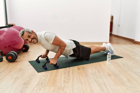 Photo for Middle age grey-haired man smiling confident training push up at sport center - Royalty Free Image