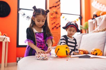 Photo for Adorable boy and girl having halloween party holding candies at home - Royalty Free Image