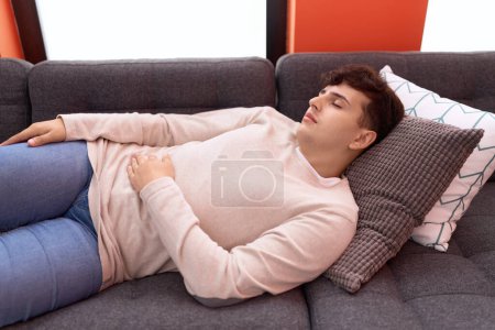 Téléchargez les photos : Non binary man lying on sofa sleeping at home - en image libre de droit