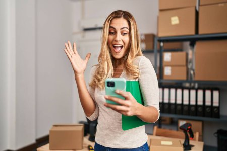 Téléchargez les photos : Jeune femme blonde ecommerce travailleur d'affaires en utilisant smartphone au bureau - en image libre de droit