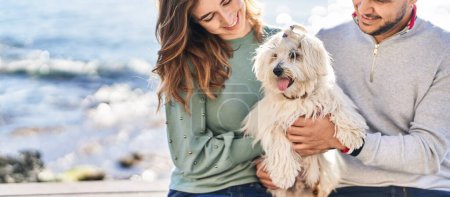 Photo for Man and woman holding dog hugging each other at seaside - Royalty Free Image