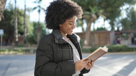 Photo for African american woman smiling confident reading book at street - Royalty Free Image