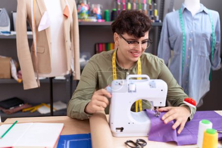 Téléchargez les photos : Non binary man tailor smiling confident using sewing machine at atelier - en image libre de droit
