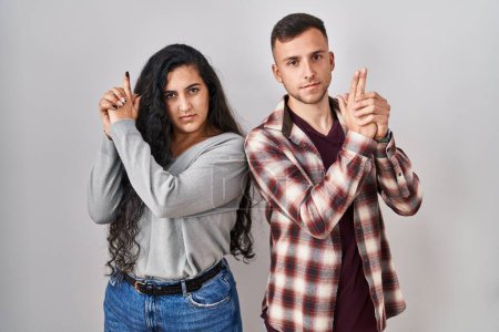 Photo for Young hispanic couple standing over white background holding symbolic gun with hand gesture, playing killing shooting weapons, angry face - Royalty Free Image