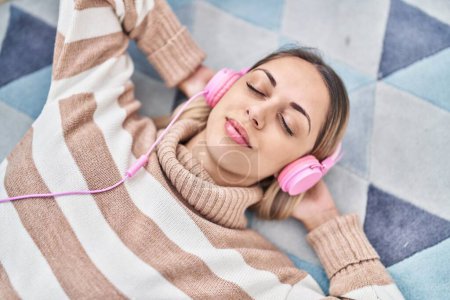 Foto de Mujer joven escuchando música tumbada en el suelo en casa - Imagen libre de derechos