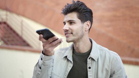 Téléchargez les photos : Young hispanic man smiling confident sending voice message by smartphone at street - en image libre de droit