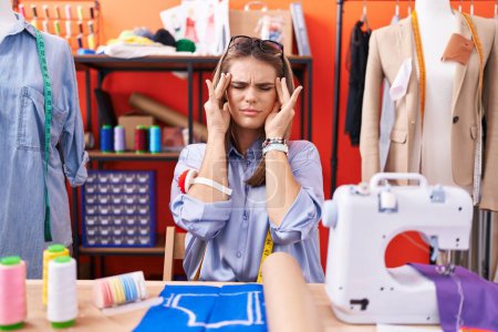 Photo for Hispanic young woman dressmaker designer at atelier room with hand on head, headache because stress. suffering migraine. - Royalty Free Image