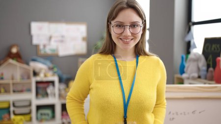 Foto de Young blonde woman preschool teacher smiling confident standing at kindergarten - Imagen libre de derechos