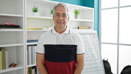 Photo for Middle age man with grey hair teaching standing by white board at university classroom - Royalty Free Image