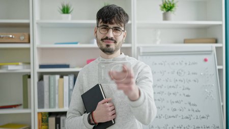 Téléchargez les photos : Jeune homme hispanique professeur debout pointant vers la caméra à l'université salle de classe - en image libre de droit
