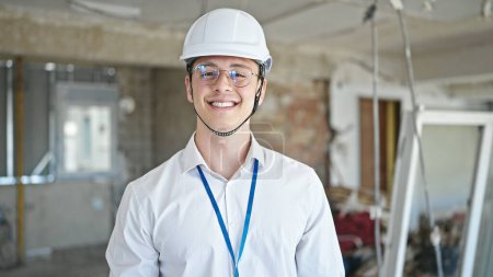 Téléchargez les photos : Jeune homme hispanique architecte souriant confiance debout sur le chantier de construction - en image libre de droit