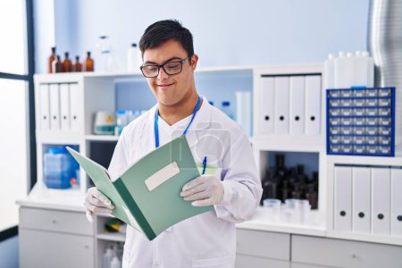 Photo for Down syndrome man wearing scientist uniform reading notebook at laboratory - Royalty Free Image