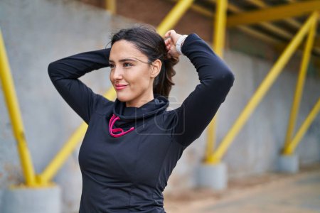 Photo for Young hispanic woman wearing sportswear combing hair with hands at street - Royalty Free Image