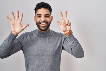 Photo for Hispanic man with beard standing over white background showing and pointing up with fingers number eight while smiling confident and happy. - Royalty Free Image