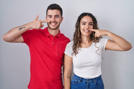 Téléchargez les photos : Jeune couple hispanique debout sur fond isolé pointant avec le doigt de la main vers le visage et le nez, souriant gai. concept de beauté - en image libre de droit