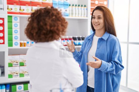 Photo for Two women pharmacist and customer speaking at pharmacy - Royalty Free Image