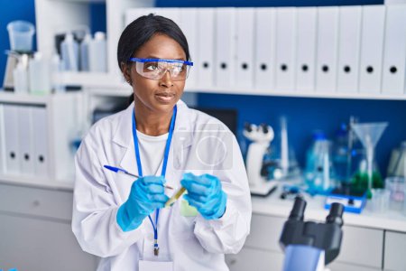 Photo for Young african american woman scientist writing on test tube at laboratory - Royalty Free Image