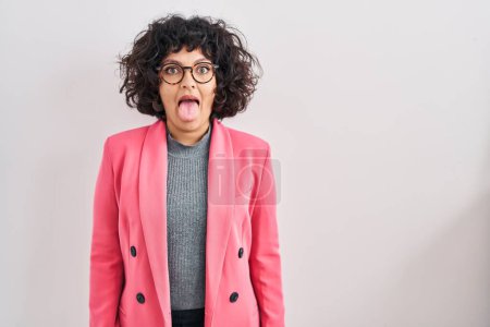 Foto de Mujer hispana con el pelo rizado de pie sobre el fondo aislado sacando la lengua feliz con expresión divertida. concepto de emoción. - Imagen libre de derechos