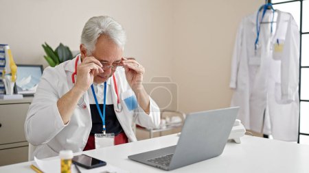 Foto de Hombre de mediana edad con médico de pelo gris estresado trabajando en la clínica - Imagen libre de derechos
